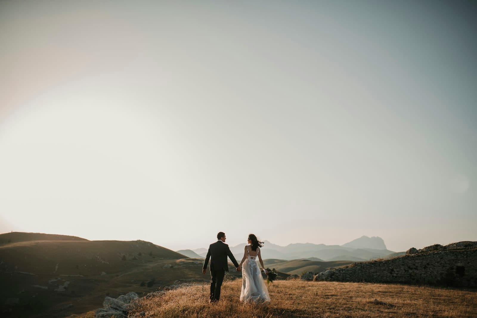 Casal de noivos de mãos dadas ao pôr do sol
